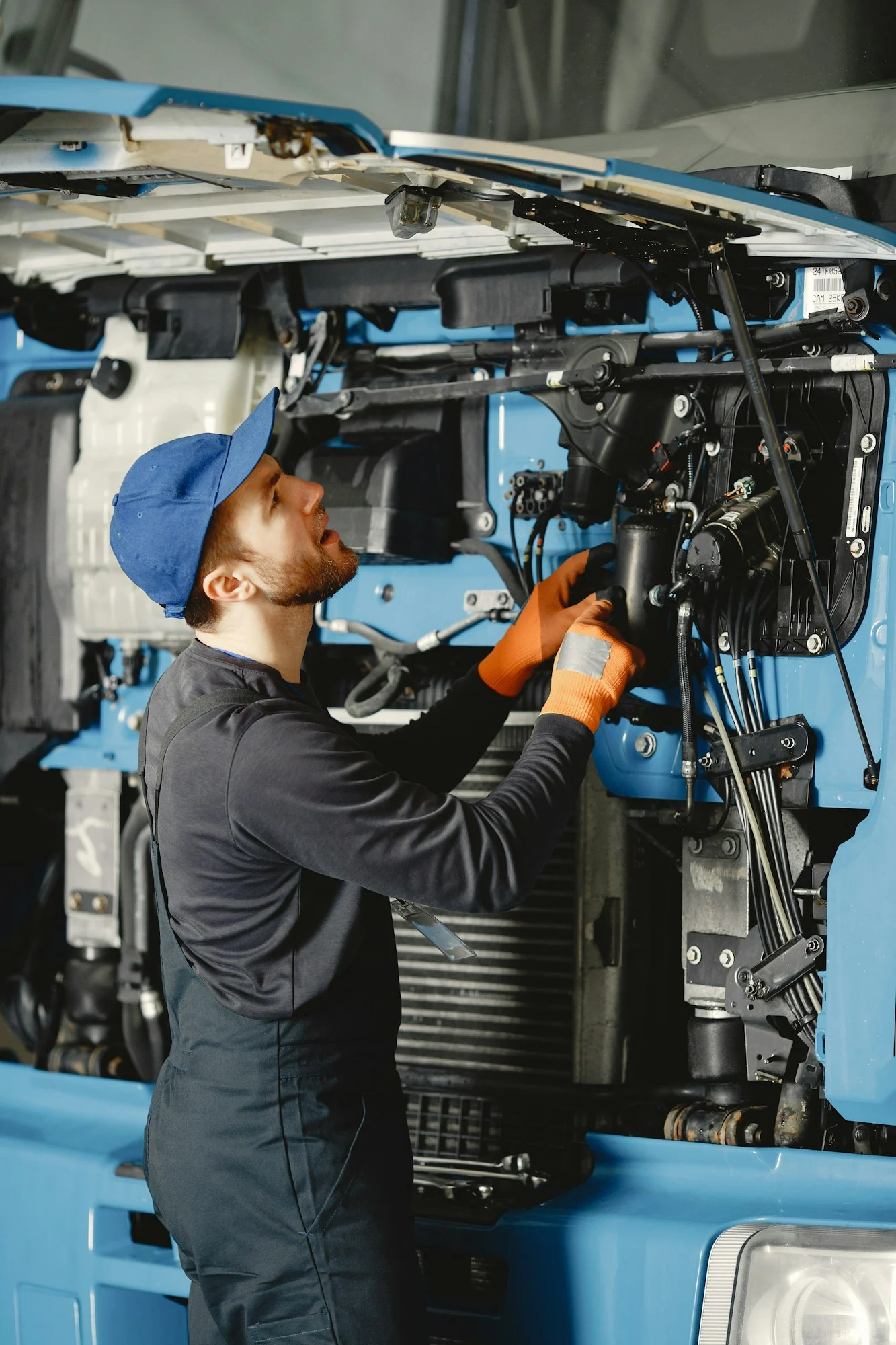 Worker checks quality of truck in garage in uniform